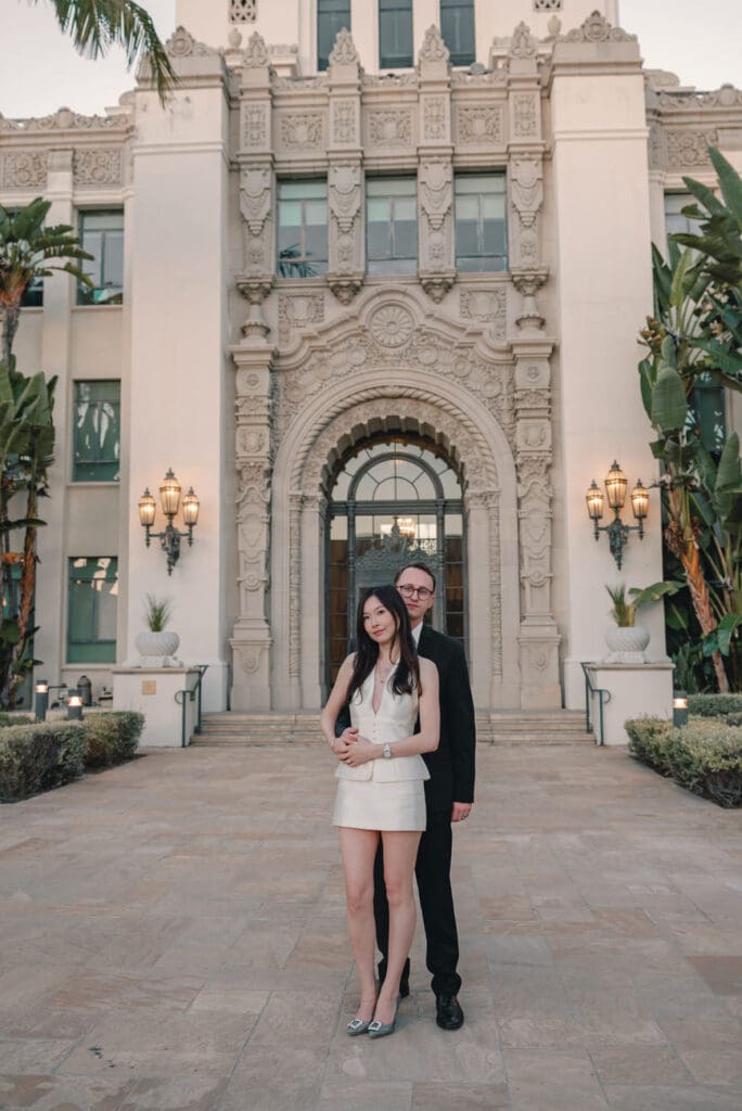 Couple posing in front of the ornate Beverly Hills City Hall entrance during an engagement session