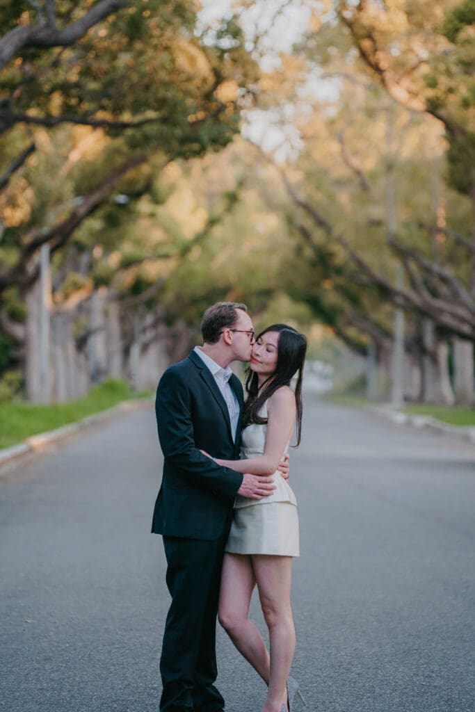 Couple dancing under a canopy of trees on a residential Beverly Hills street during an engagement photo session