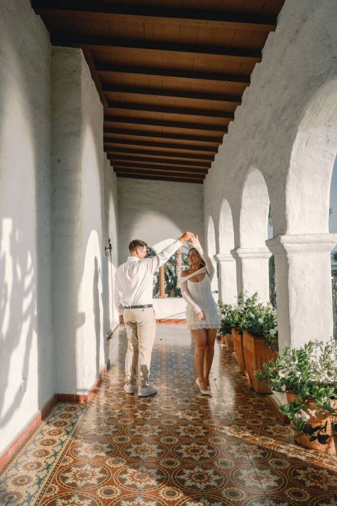 Couple walking through the arched hallway at Casa Romantica during their San Clemente engagement session.