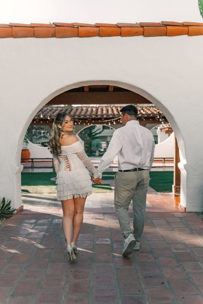 Couple walking through the arched walkways at Casa Romantica during their San Clemente engagement session.
