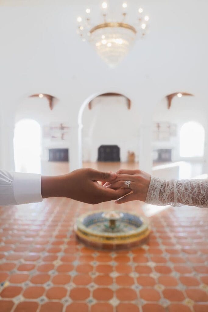 Close-up of a couple holding hands inside the main salon at Casa Romantica in San Clemente, California.