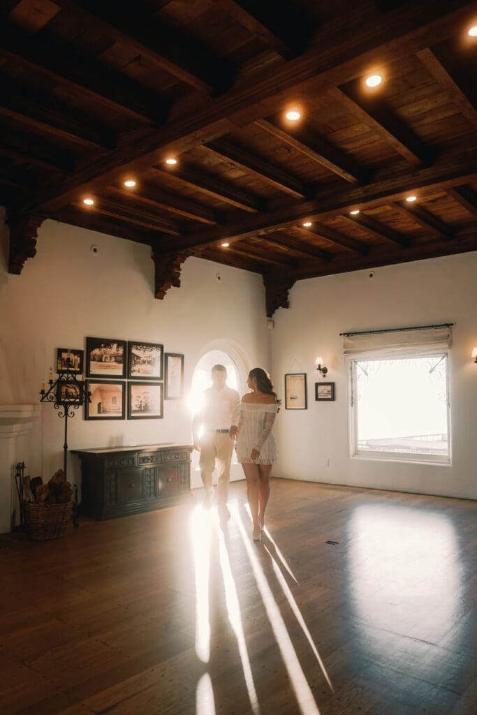 Couple standing in soft window light inside a museum room at Casa Romantica in San Clemente, California.