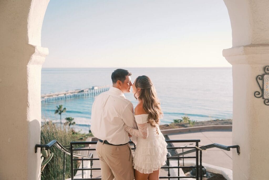 Couple posing under the ocean view arches for Casa Romantica engagement photos in San Clemente, California.