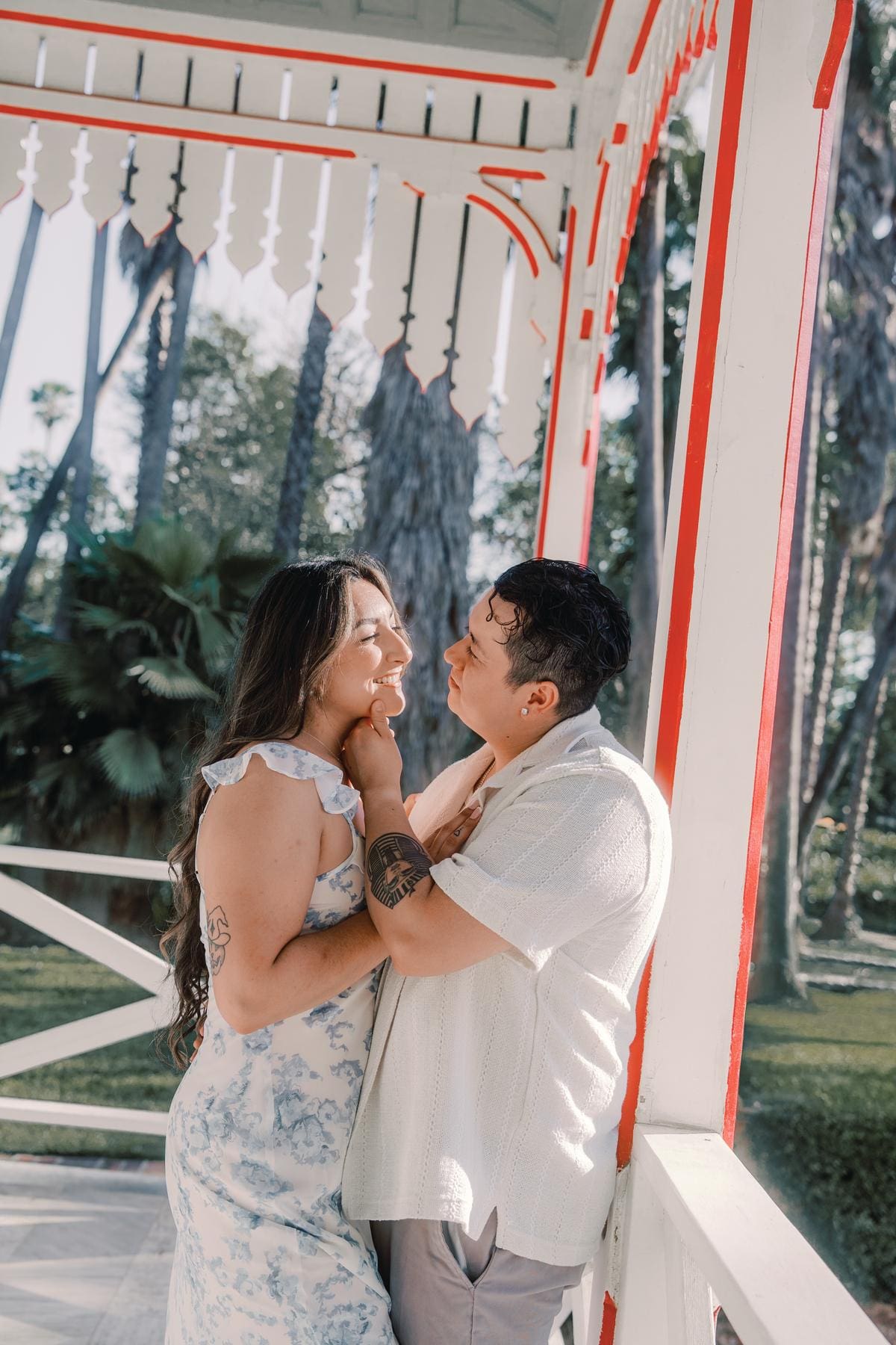 Close portrait of a couple laughing together on a red-trimmed cottage porch.