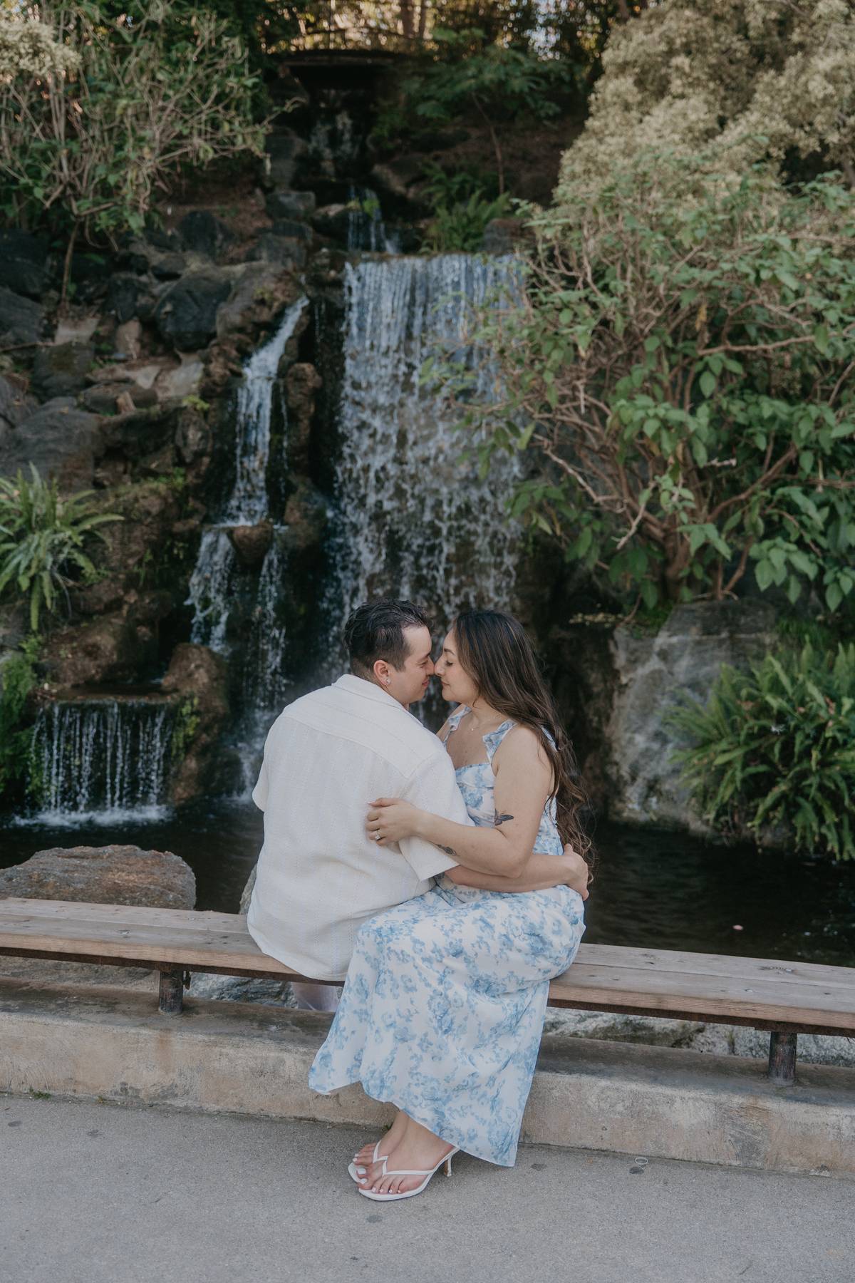 Couple sitting together in front of Meyberg Waterfall at the LA Arboretum.