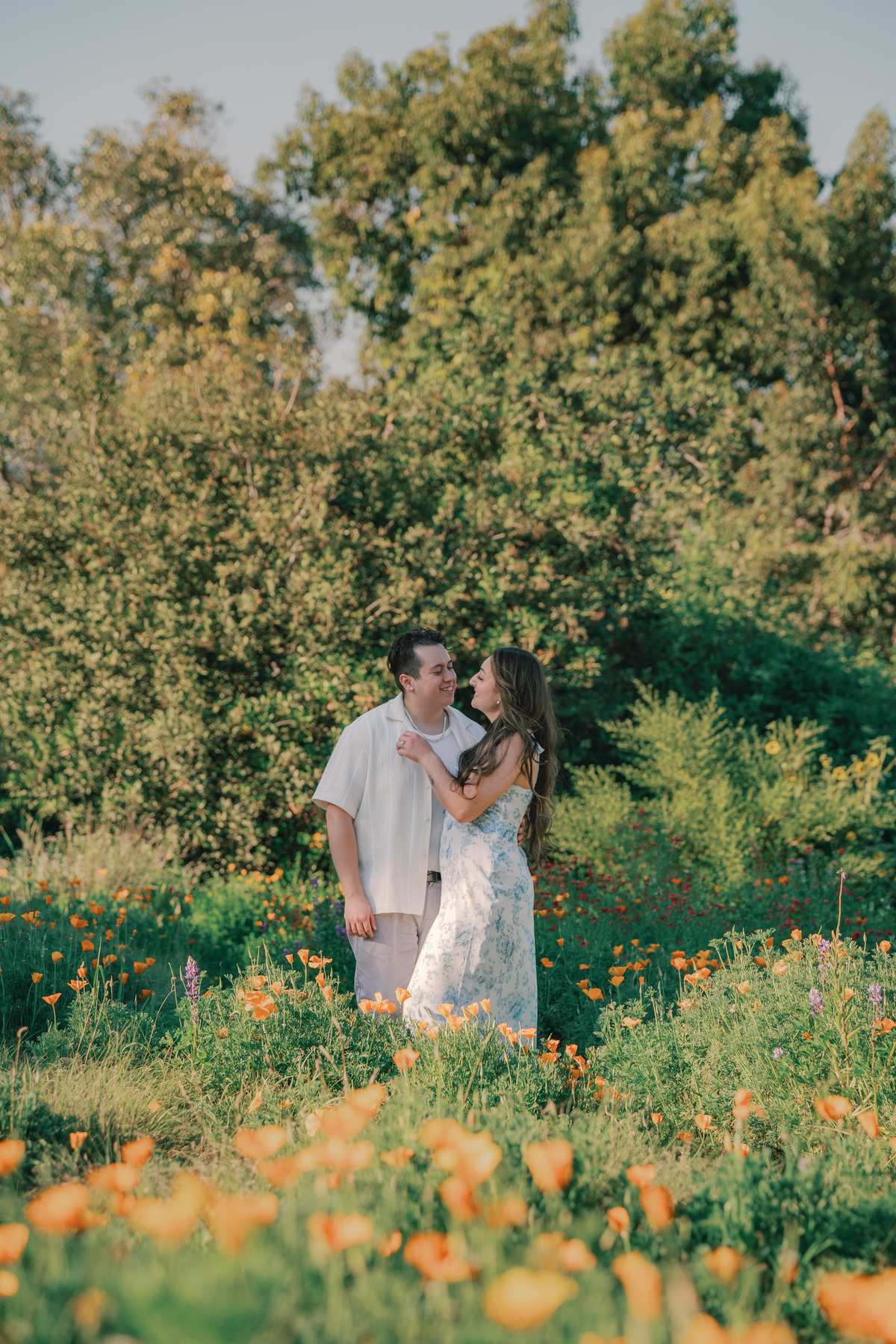 Couple standing among orange wildflowers and layered greenery at the LA Arboretum.