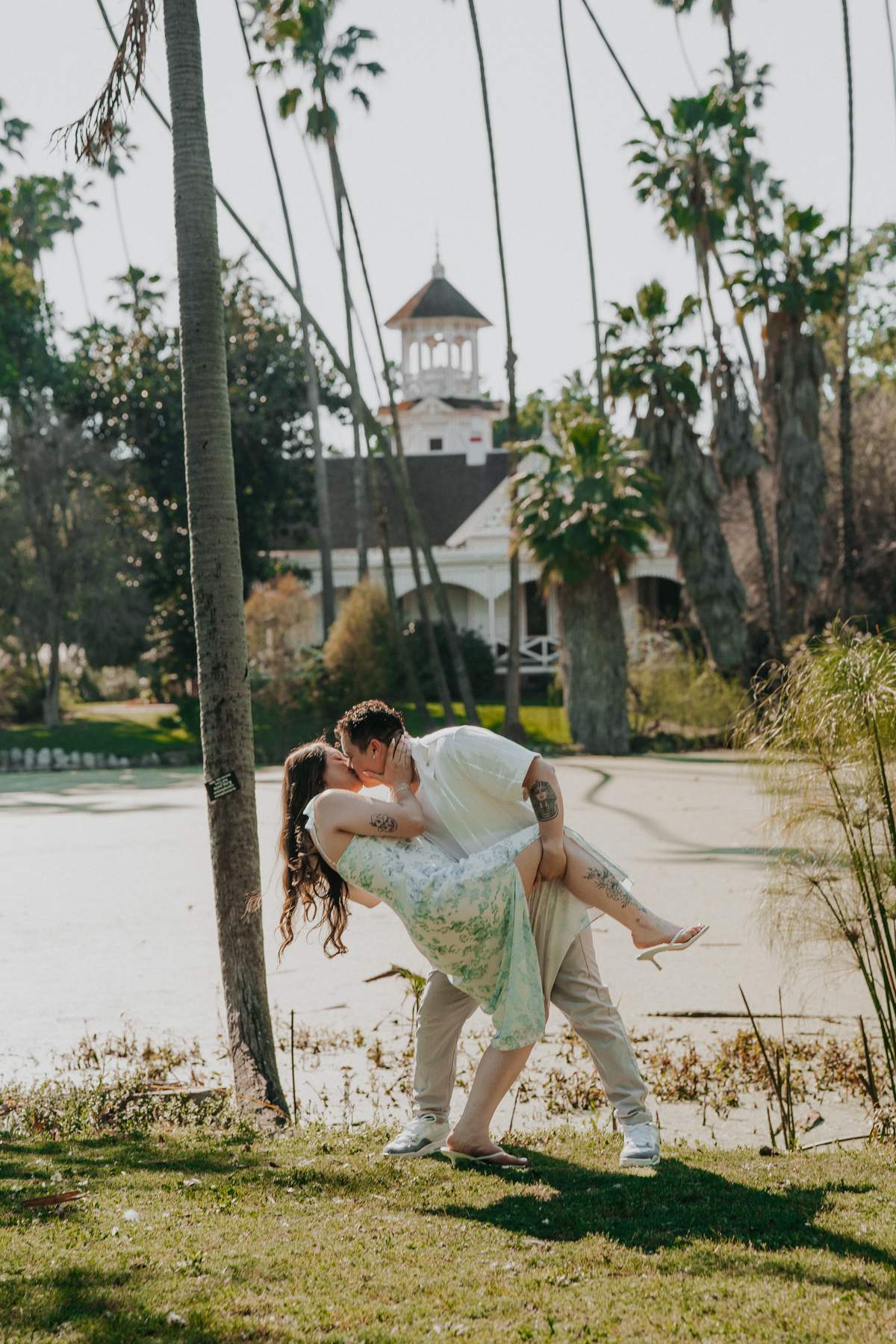 Couple sharing a playful dip with Queen Anne Cottage visible behind them.