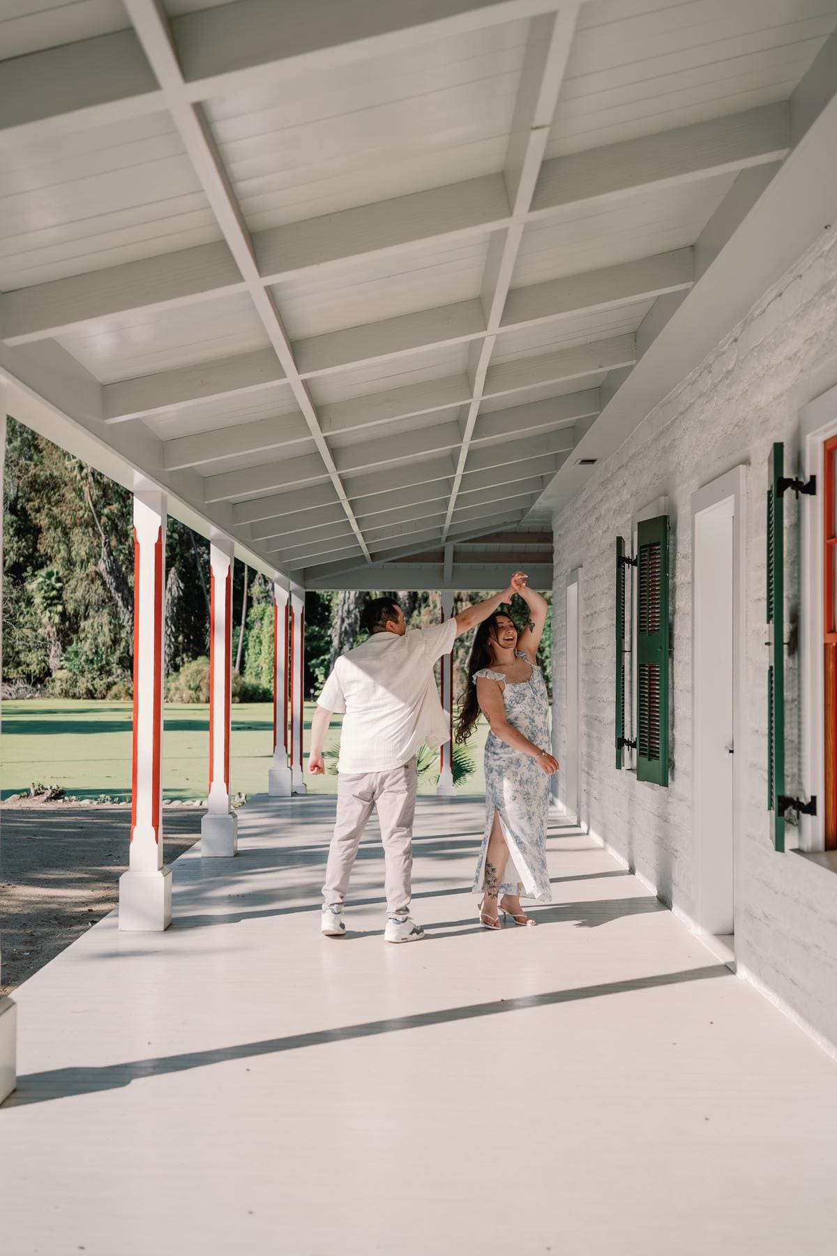 Couple dancing along a long white porch with red architectural details.