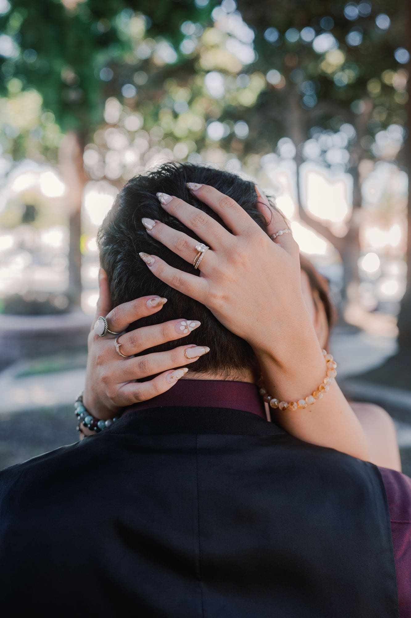 A close view of the bride’s hand and ring as she embraces her partner outdoors.