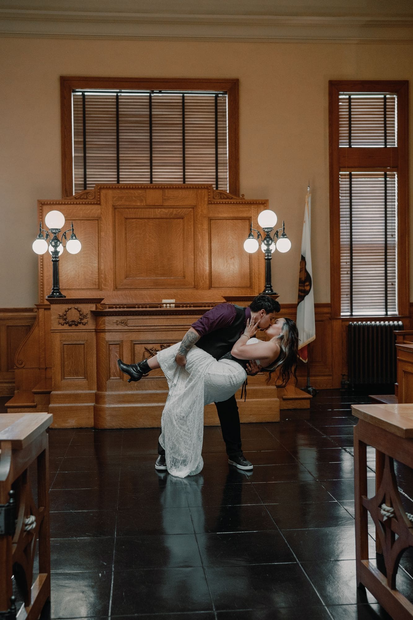 The couple shares a dip kiss in the wood-paneled room.