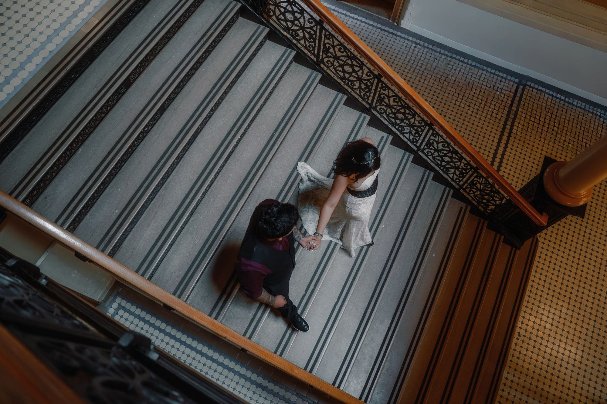 An overhead view of the couple holding hands on the interior stairs of the Old Orange County Courthouse in Santa Ana.