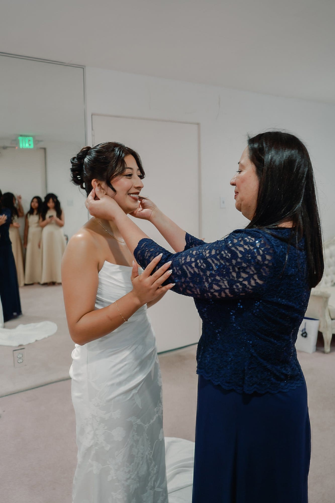 A woman reaches toward the bride’s face in the bridal suite at The Santa Anita Church in Arcadia, California.