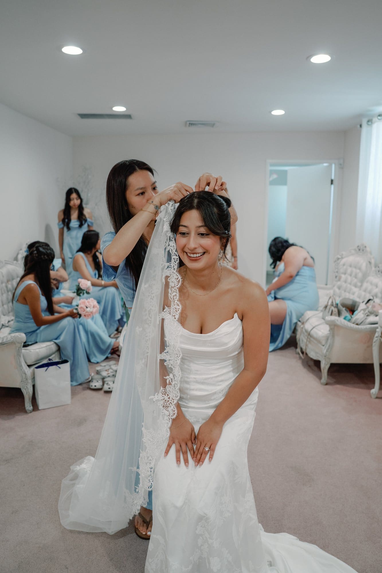 The bride laughs while attendants arrange her veil at The Santa Anita Church in Arcadia, California.