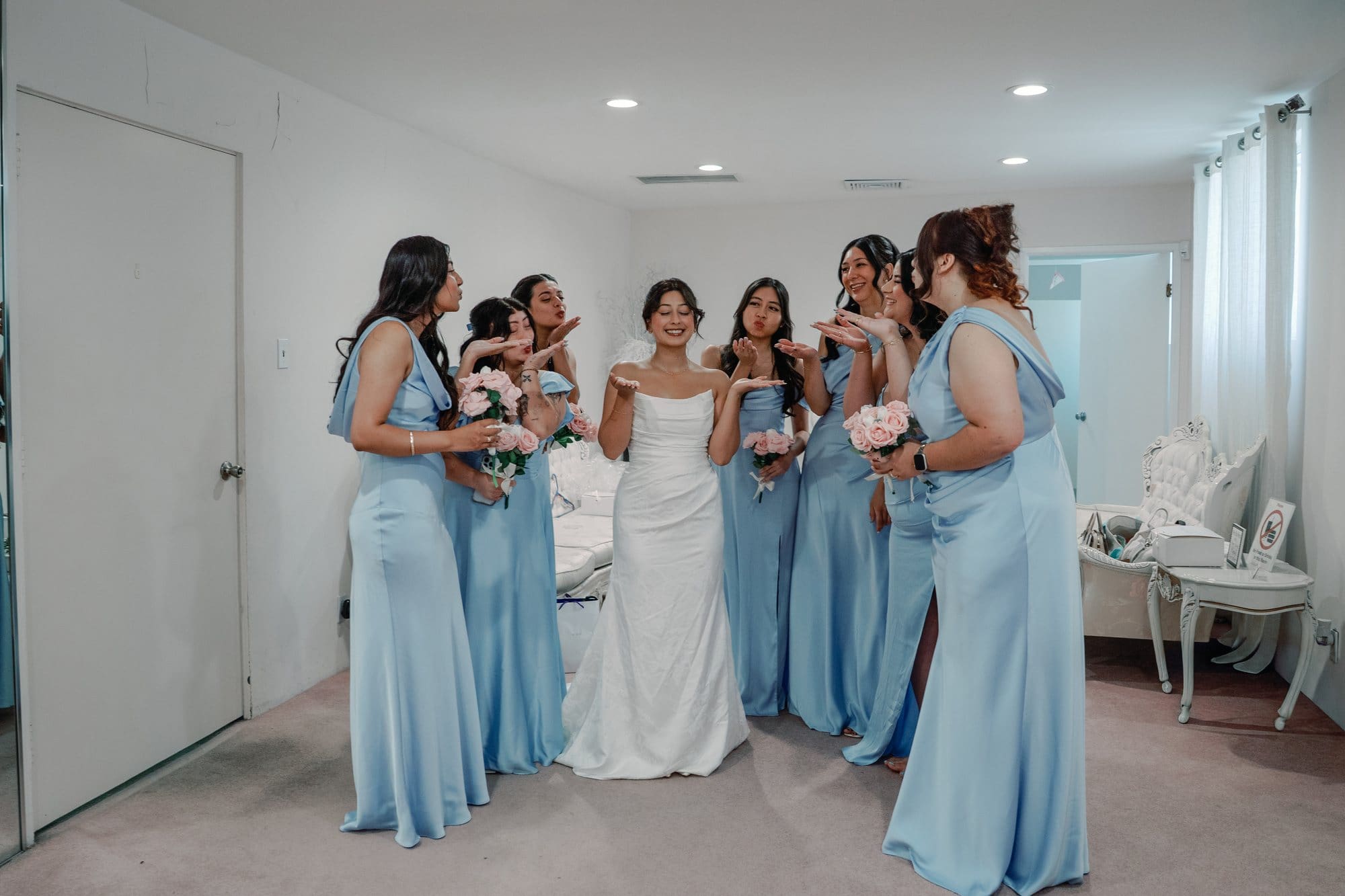 The bride stands with bridesmaids in pale blue dresses indoors at The Santa Anita Church in Arcadia, California.