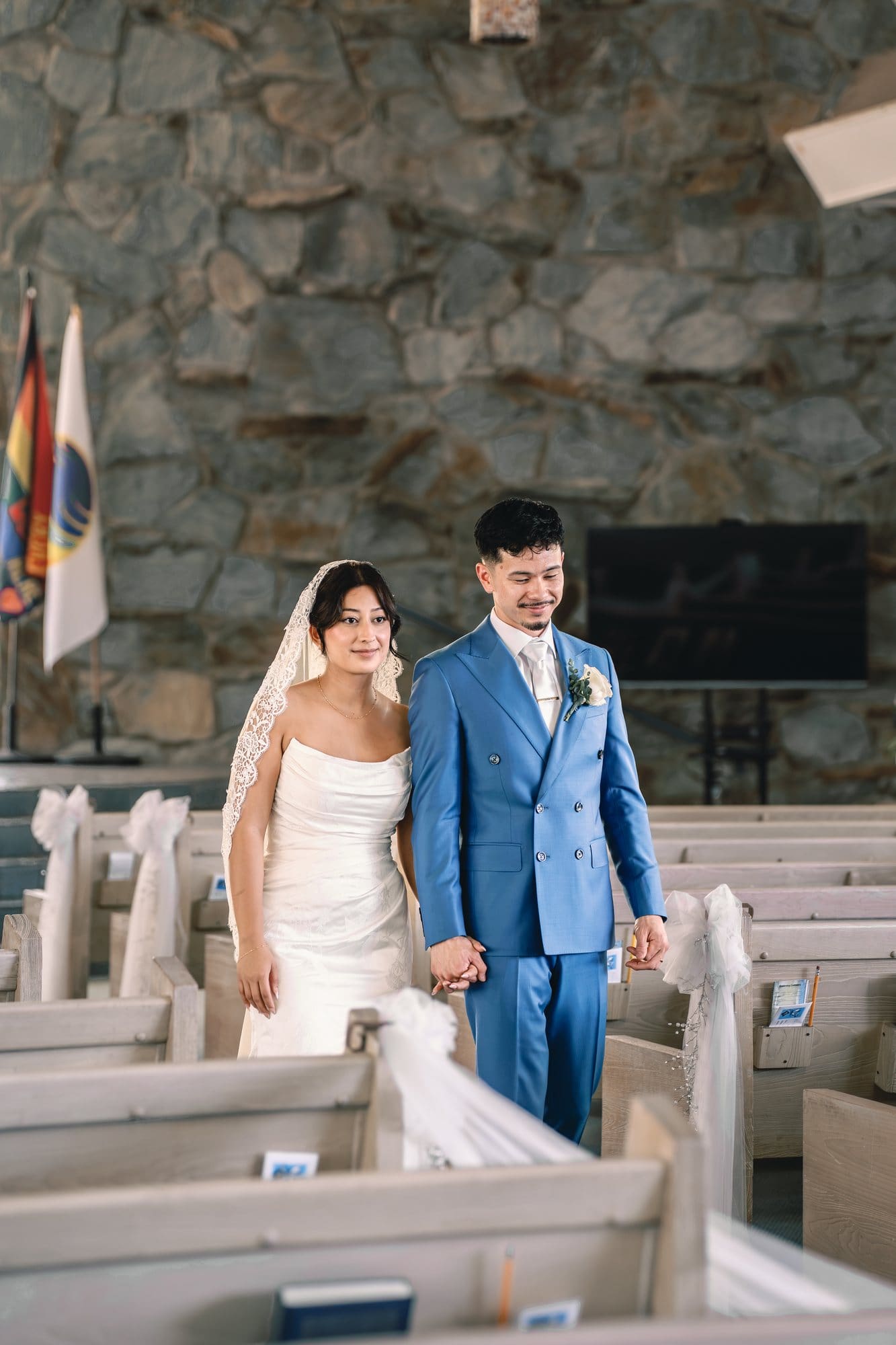 The couple walks hand in hand between the sanctuary pews at The Santa Anita Church in Arcadia, California.