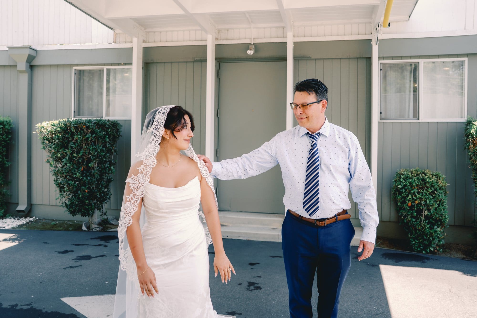 The bride’s dad reaches toward her shoulder during their first look at The Santa Anita Church in Arcadia, California.