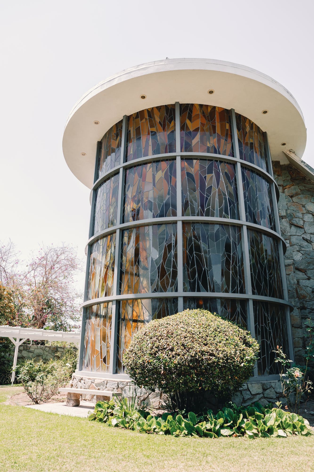 The cylindrical stained glass tower rises beside the garden at The Santa Anita Church in Arcadia, California.
